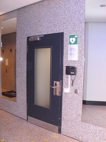 AED hinter der rechten, verschlossenen Tür + Tür-Telefon